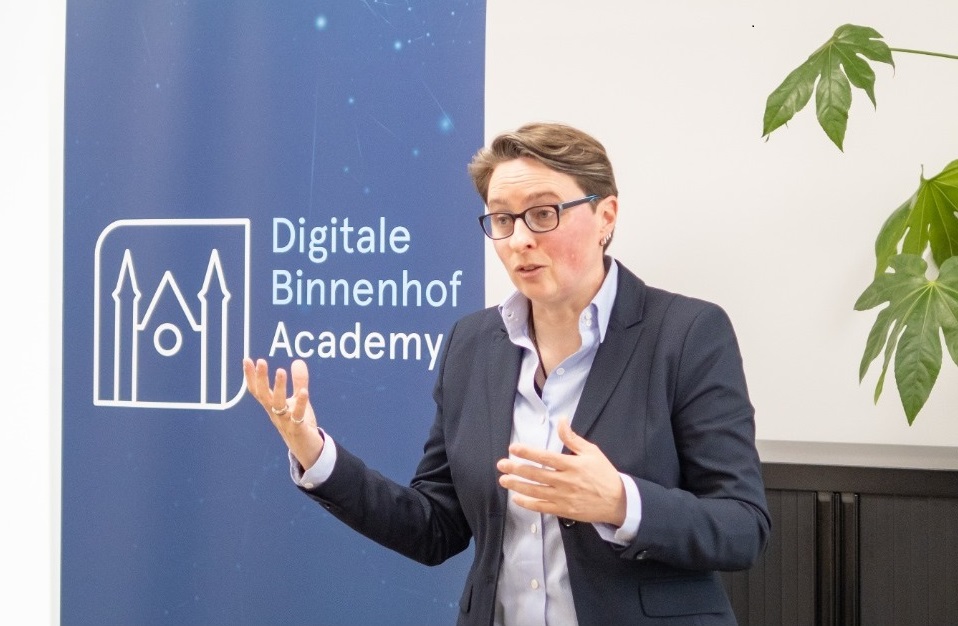 Foto Bibi van den Berg voor scherm met logo Digitale Binnenhof Academy